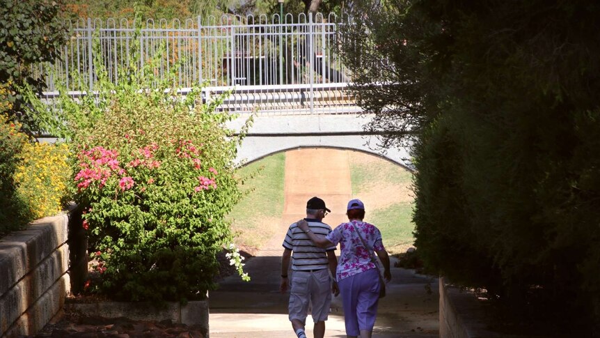 A man and woman embrace as they walk under an underpass