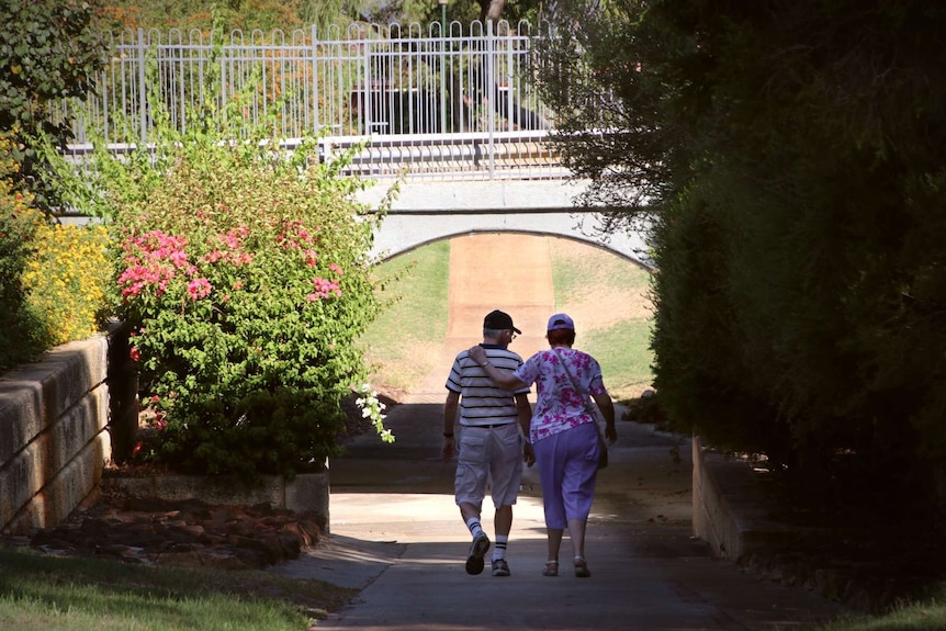 A man and woman embrace as they walk under an underpass