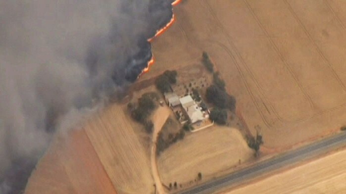 Fire burns near a house