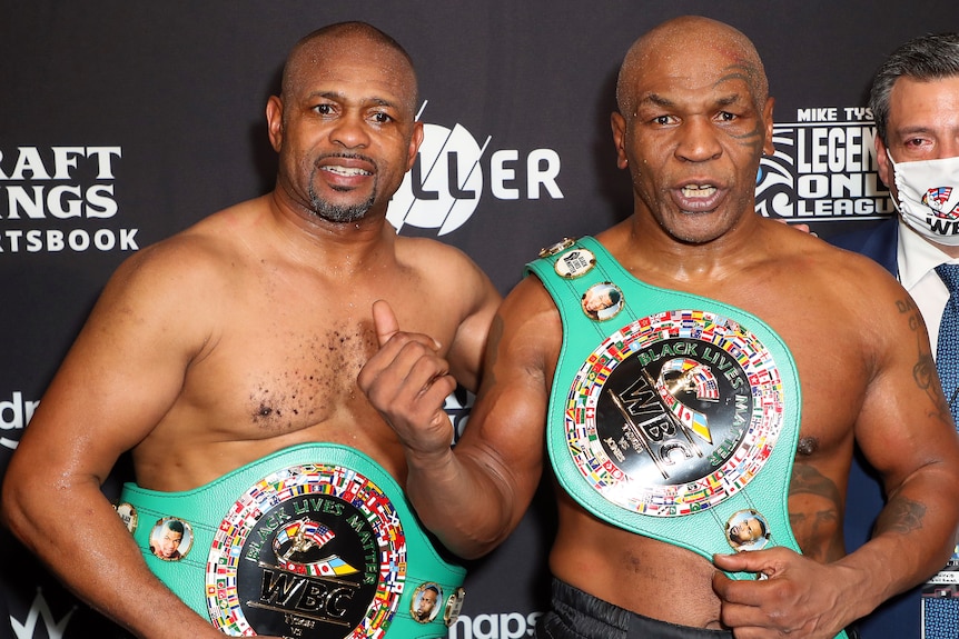 Roy Jones Jr and Mike Tyson wear green boxing belts