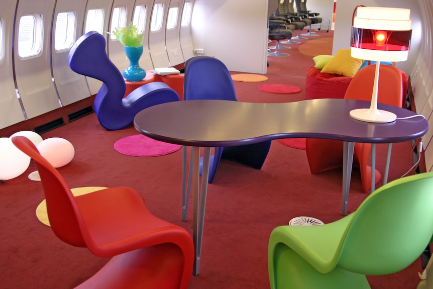 Colourful chairs and tables on board a stripped-down airplane.