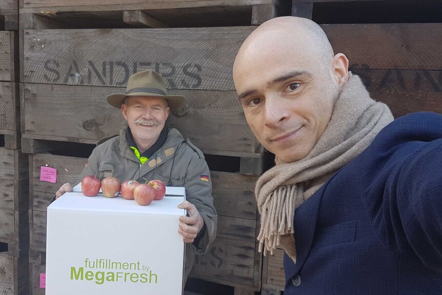 Apple producer Kevin Sanders holds up his apples standing next to Megafresh found Alex Stefan