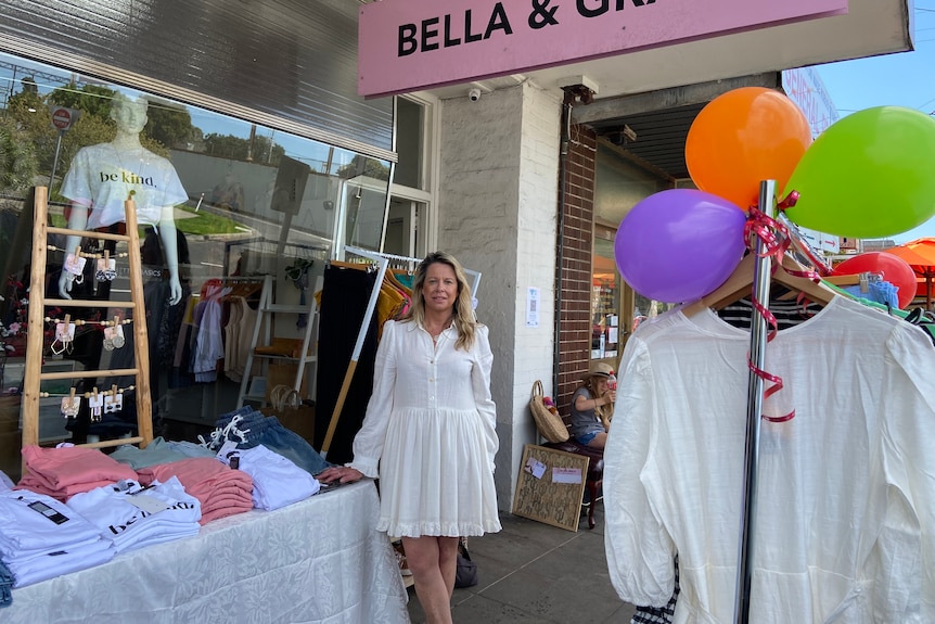 A woman operating a clothes store outside.