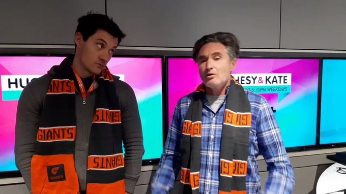 Ed Kavalee and Dave Hughes stand in a radio studio wearing GWS Giants scarves.