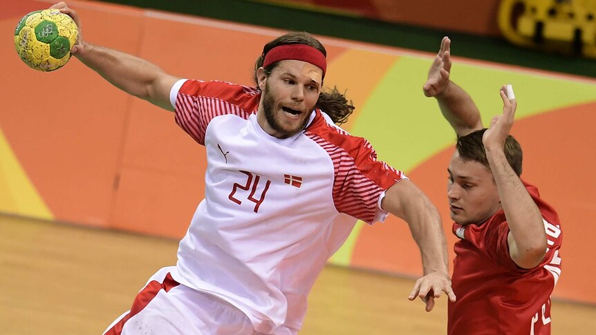 Mikkel Hansen from Denmark jumps to shoot the ball past a Polish player during the men's semi-final handball match in Rio.