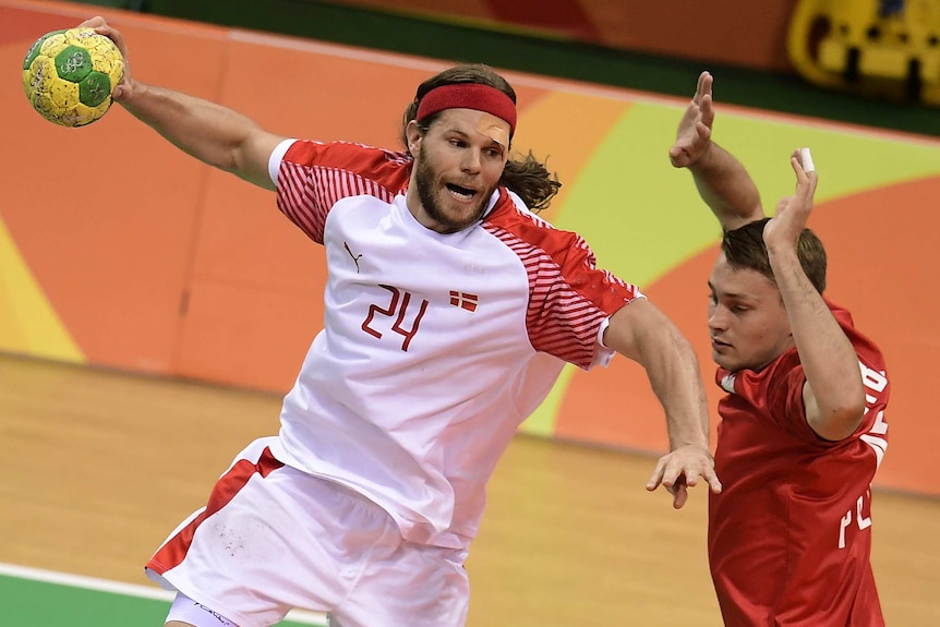 Mikkel Hansen from Denmark jumps to shoot the ball past a Polish player during the men's semi-final handball match in Rio.