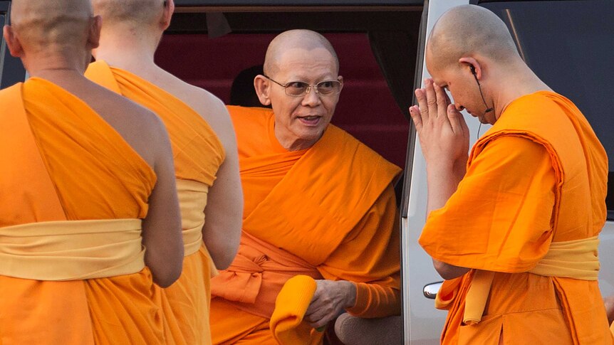 Phra Dhammachayo, founder of the Dhammakaya sect, is surrounded by fellow monks