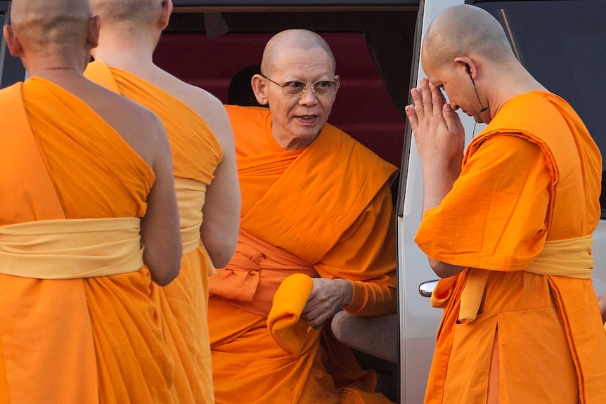 Phra Dhammachayo, founder of the Dhammakaya sect, is surrounded by fellow monks