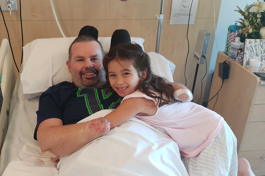 Buddy Mliler hugs daughter Jayda in his hospital bed