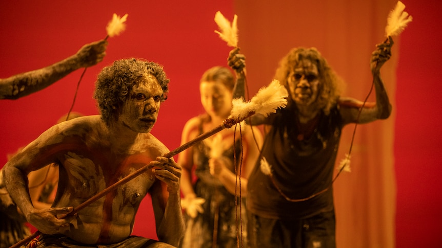 A man and a woman in ceremonial dress on stage.