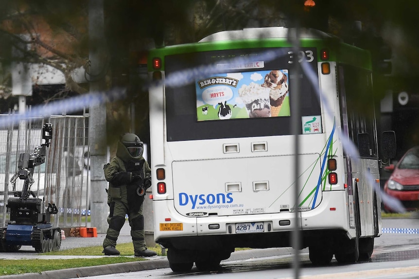 A bomb squad member and a robot investigate a bus in Moonee Ponds.