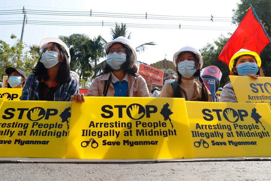 Mandalay University graduates hold posters that say "Stop Arresting People illegally at midnight"