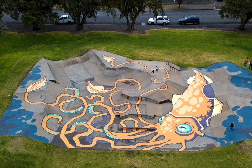 A mural of a squid on the ground of a skatepark.