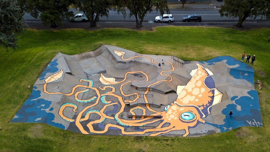 A mural of a squid on the ground of a skatepark.