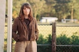 A woman standing in front of a fence.