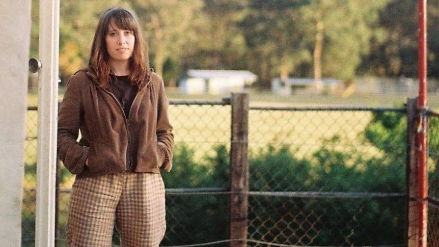 A woman standing in front of a fence.