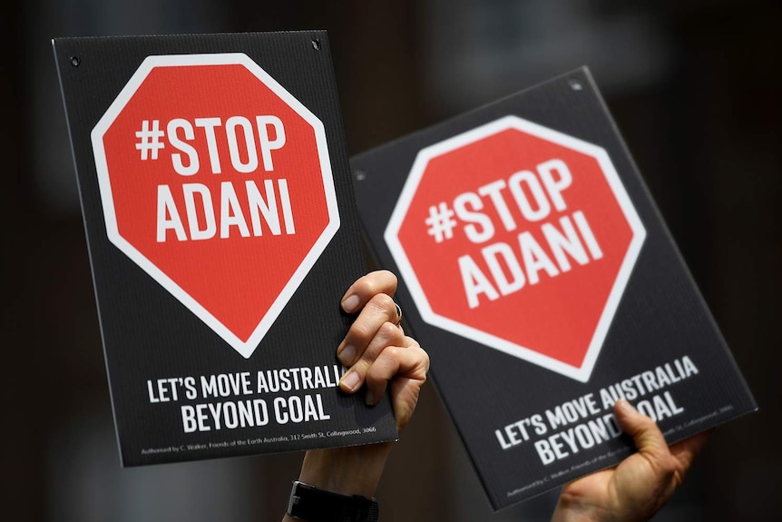 Close-up of Stop Adani signs held by protesters.