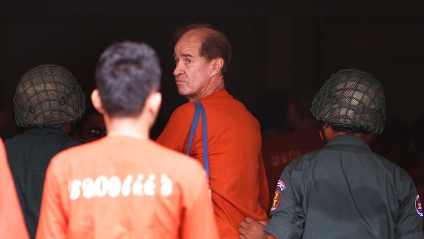 James Ricketson looks behind him as he walks into court