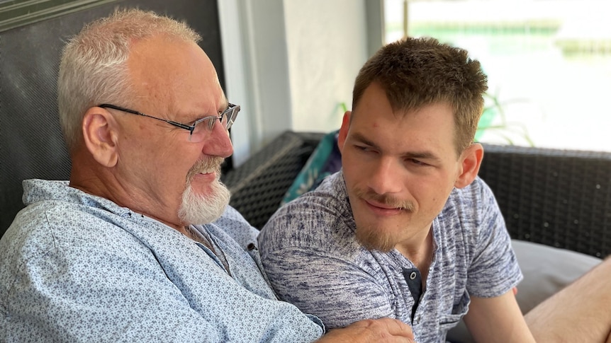 Ron Moore smiles as he sits with his son Lachlan at their home.