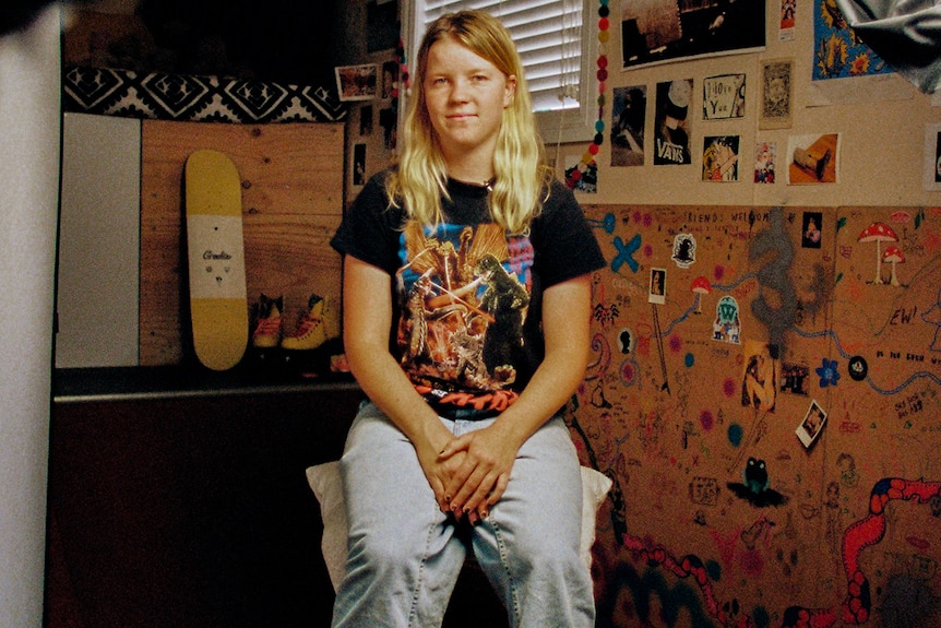 Interior scene Poppy wits in her bedroom surrounded by skateboards and trophies