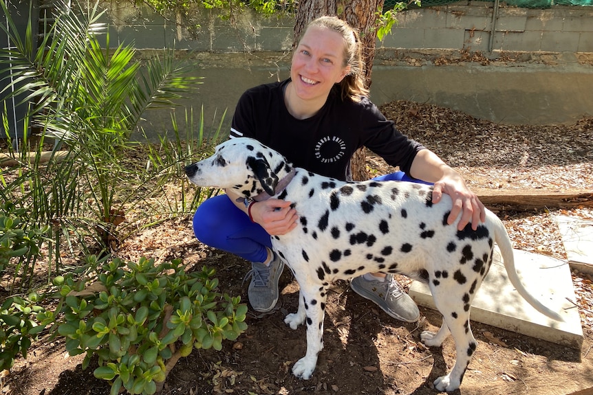 A woman holding on to a black and white spotty dog