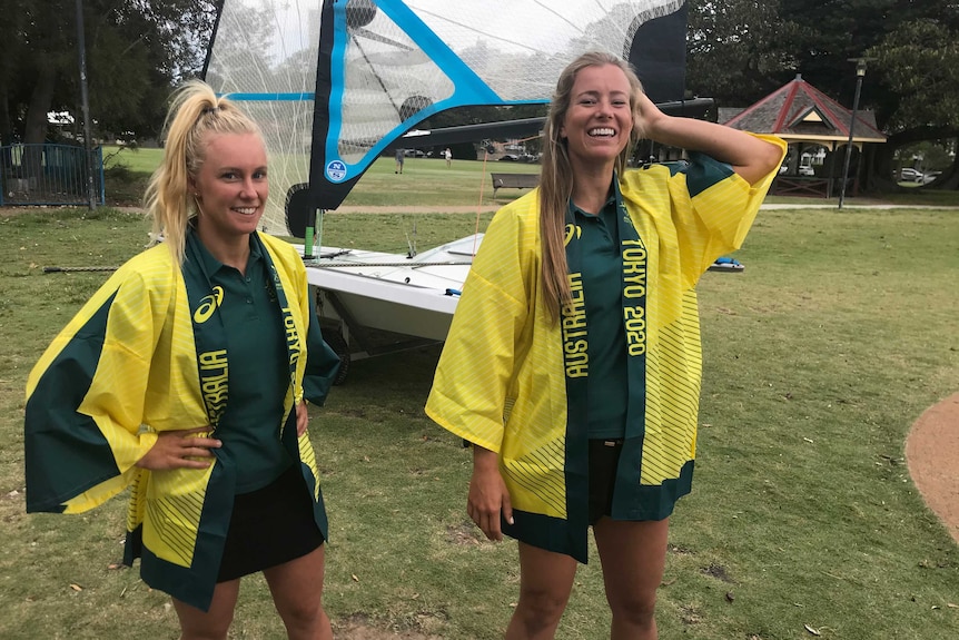 Two women stand in front of a sailing boat, in the park.