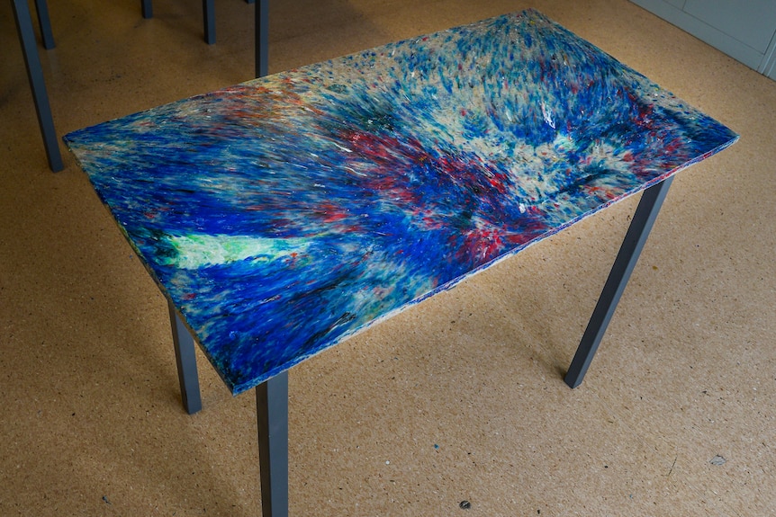 A speckled bright blue desk in a classroom.