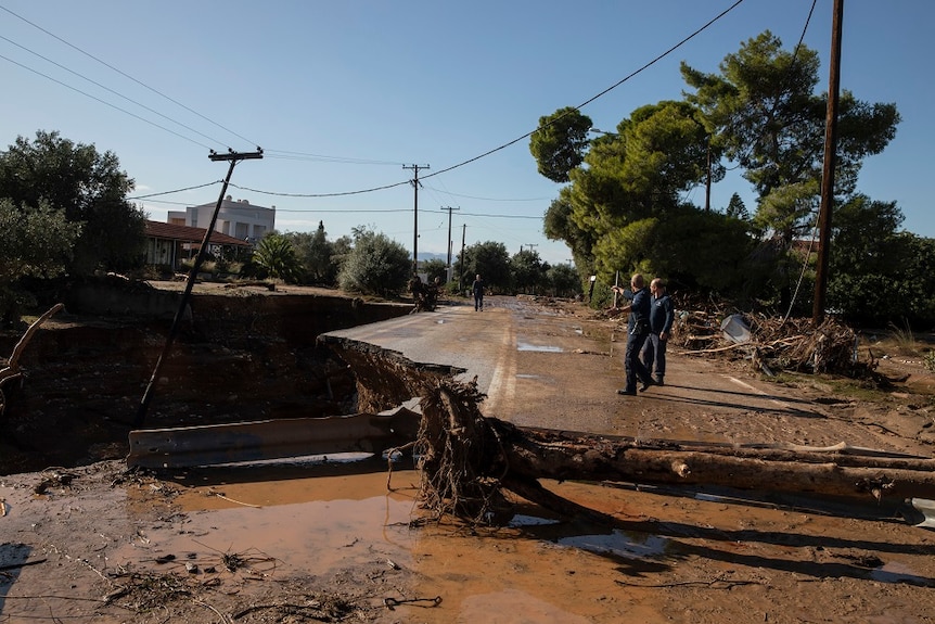People inspect a destroyed road.