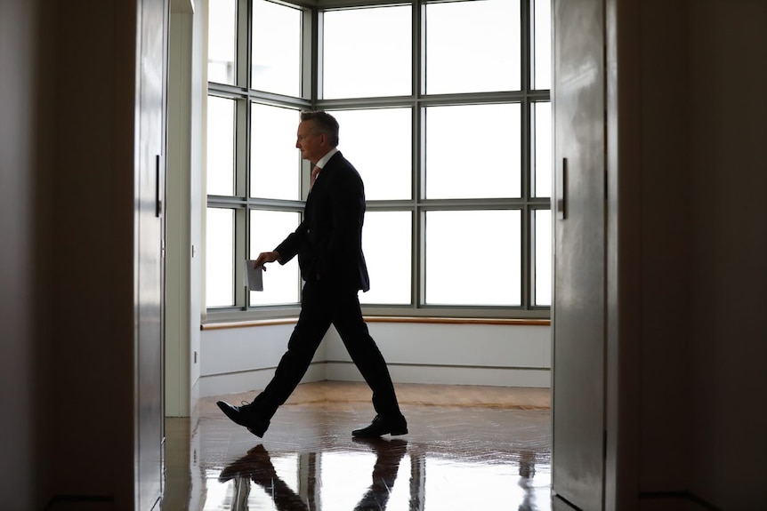 Chris Bowen walks along a corridor in Parliament House.