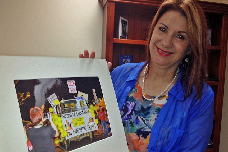 Douglas Mayor Julia Leu holds up a photo of a street rally