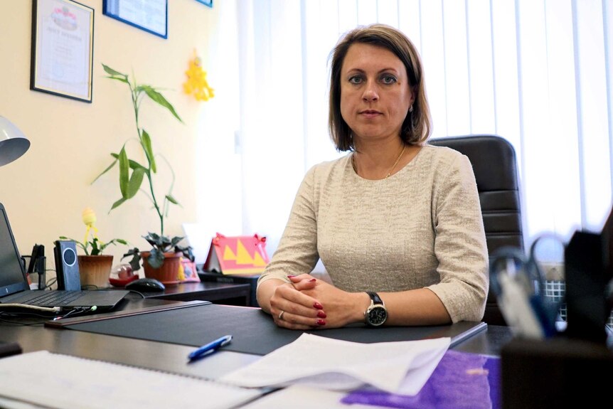 Natalia Syvoraksha sits at her desk, looking toward the camera.