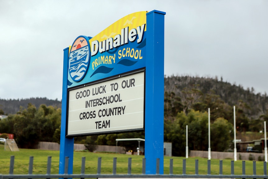 A sign outside a primary school with a football ground in the background