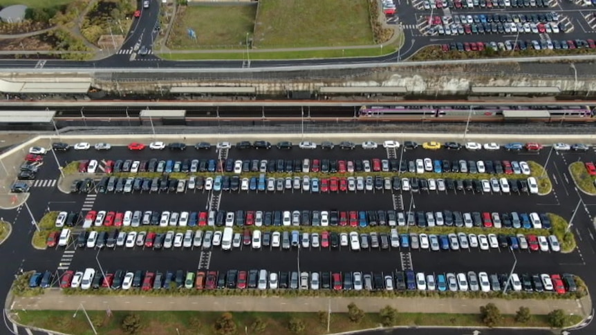 The commuter car park is full in Wyndham, Melbourne as a train goes past.