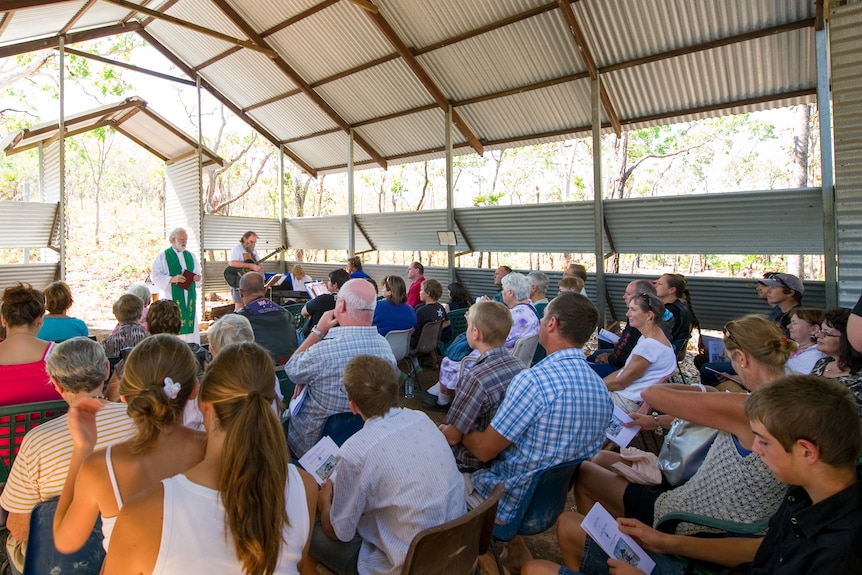 Dozens of people packed into a tiny bush church.