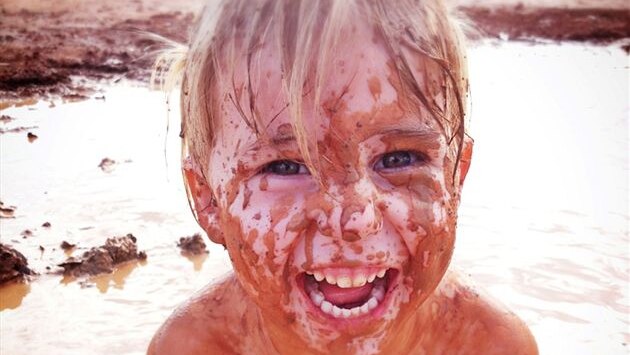 A child plays in the Centralian claypans to cool down in the summer heat.