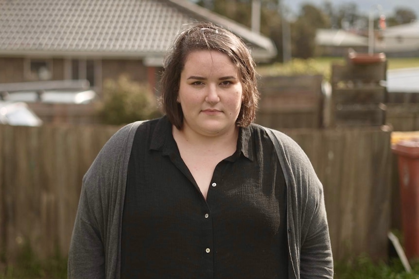 Ashley May is standing outside in front of the fence.