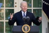 US President Joe Biden stands and speaks outdoors behind a lecturn, gesturing with his hands.