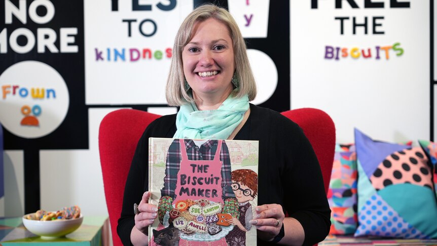 Steph Smith holds up story book with title The Biscuit Maker
