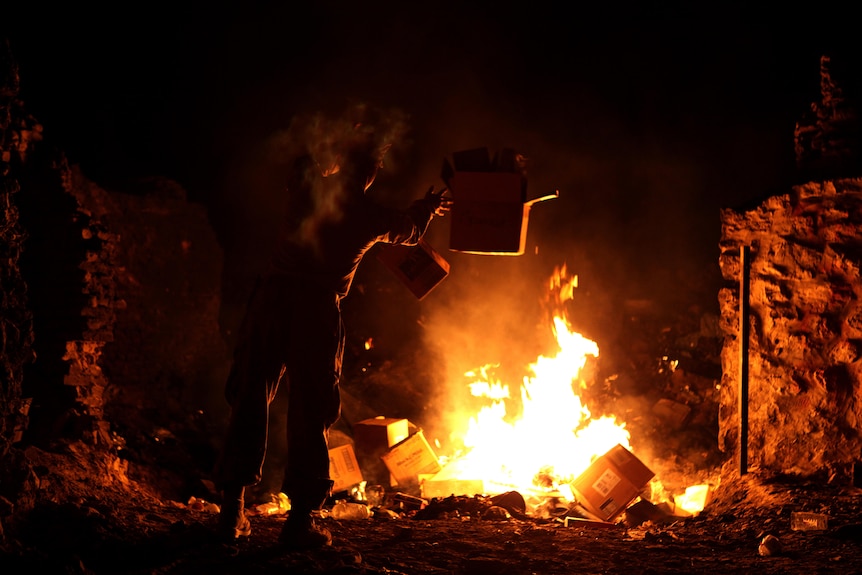 Man throwing rubbish into a burn pit.