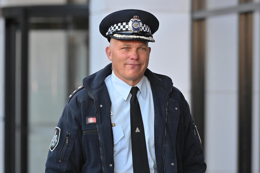 An ACT police officer in uniform walks outside a building.