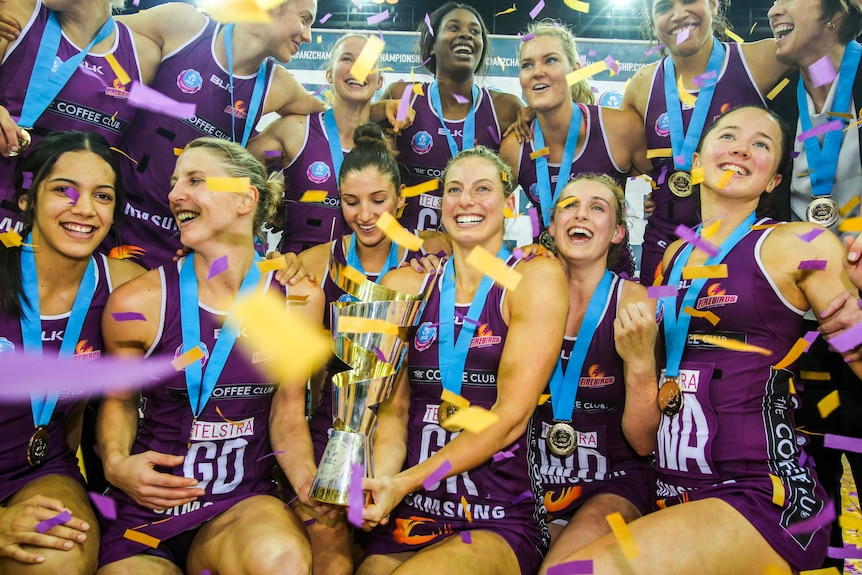 Netballers hold trophy smiling