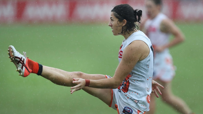 GWS Giants player Rebecca Privitelli completes her kicking motion during an AFLW game in the rain.