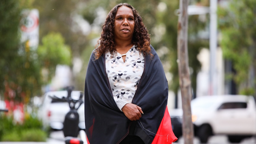 Bernadette Clarke wears an Aboriginal flag draped around her shoulders.