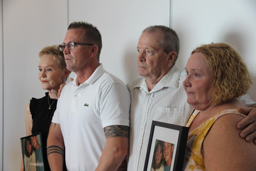 Two women and two men looking sad and holding photographs of a missing woman.