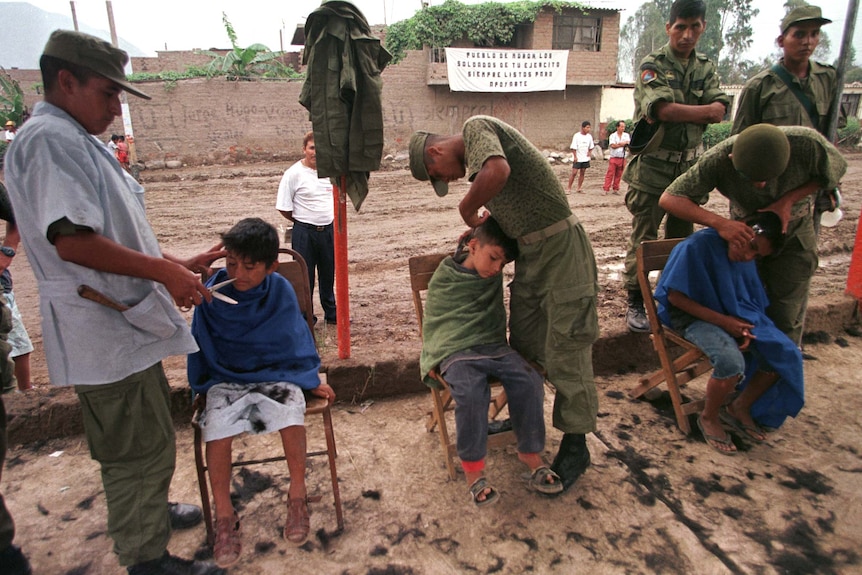Peruvian soldiers cut the hair of three boys left homeless by the 1998 March floods in the Peruvian town of Moron.