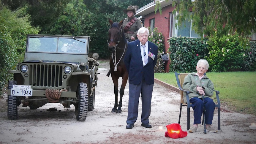 Three people and a horse and army vehicle stand on a driveway