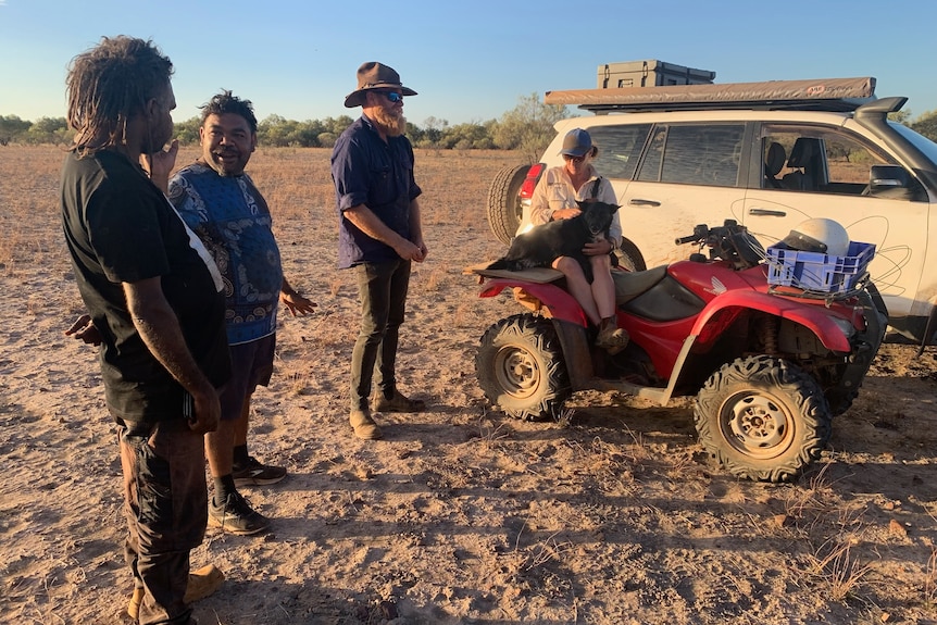 Four people, including David Whitlaw, stand near a four-wheel drive and a motorbike near Balgo, Western Australia, 2023.