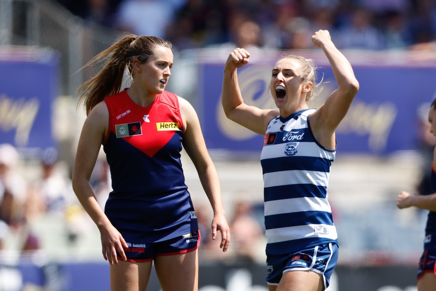 Amy McDonald pumps her fists in celebration as a Melbourne player runs past her