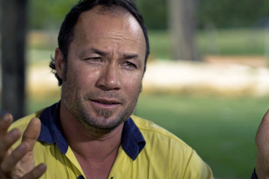 A man wears a hi-vis yellow shirt with a blue collar.