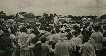 A mob of men surround one man.